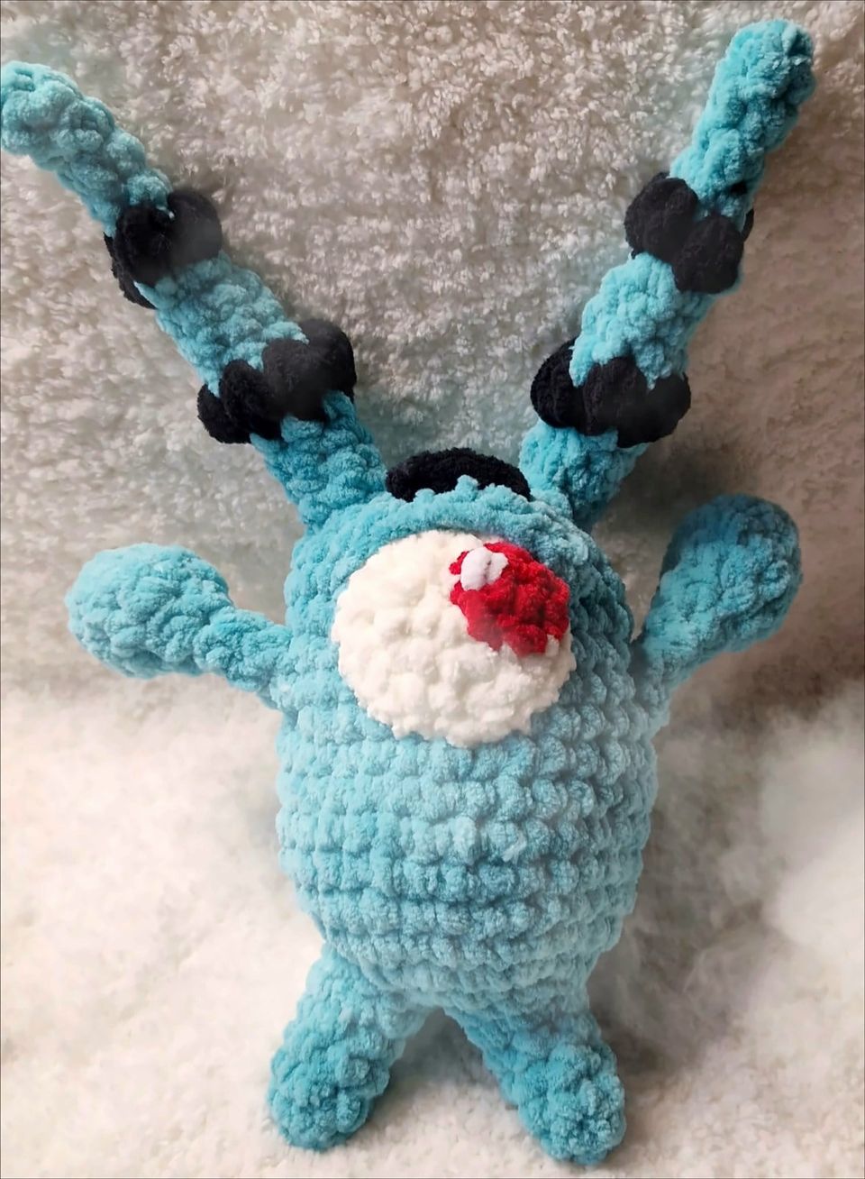 A turquoise chenille monster with two long antlers banded in black, a single large white eye patch and a red pupil
